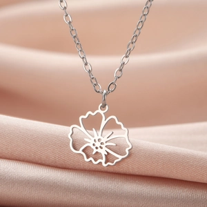 Makroaufnahme des silbernen Blumenanhängers an einer O-Kette auf rosa Satin
