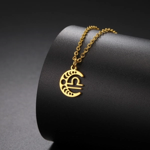 Détail macro du pendentif Balance doré avec croissant de lune et chaîne à maillons croisés