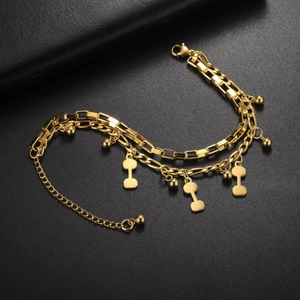 Detail of gold double-layered bracelet with dumbbell pendants and industrial style chain link