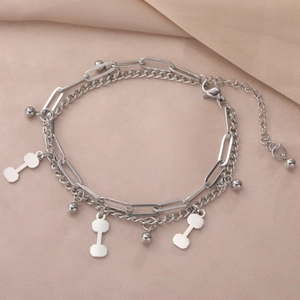 Detail of double-layer stainless steel bracelet featuring dumbbell and bead charms
