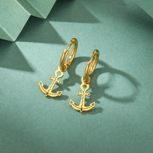 Artistic shadow play on a polished golden anchor pendant earring with marine vibes