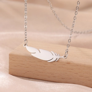 Minimalist feather pendant necklace in polished 304 stainless steel on wood stand