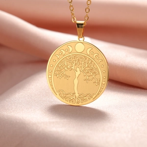 Primer plano de colgante árbol de vida dorado con silueta de mujer y lunas