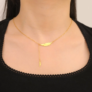 Detail of 18K gold-plated feather pendant necklace on a model wearing black lace