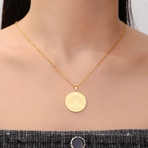 Detalle de un colgante de moneda Árbol de la Vida dorado en una cadena fina de eslabones