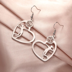 Macro view of stainless steel volleyball heart earrings on soft pink silk background