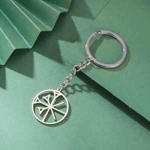 Polished stainless steel round pendant keychain featuring geometric cutout on green paper art