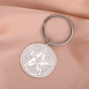 Polished stainless steel pentagram keychain with engraved mystical symbols on pink velvet