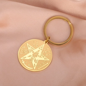 Close-up of golden stainless steel keychain with mystical pentagram and engravings
