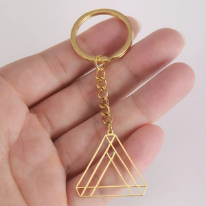 Golden stainless steel keychain with hollow geometric triangle pendant held in hand