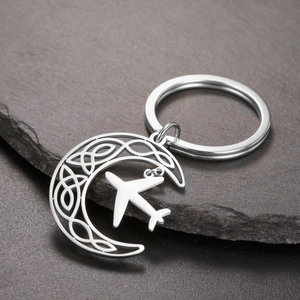 Detail view of crescent moon keychain with celtic knots and small airplane pendant