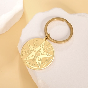 Macro shot of gold stainless steel keychain featuring a pentagram and occult engraving