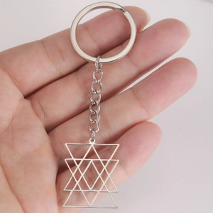 Minimalist stainless steel keychain with hollow geometric hexagram pendant held in hand