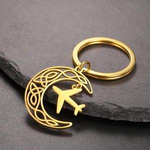 Detailed macro view of golden crescent moon keychain with airplane charm on stone