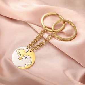 Detail view of gold and silver lion couple keychains on soft pink silk fabric