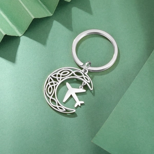 Detail of crescent moon keychain with celtic knot cutout and small airplane charm