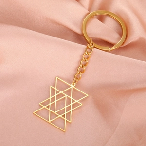 Detail of a golden geometric star keychain on soft pink satin fabric background