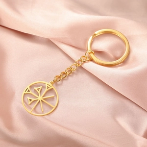 Detail of a polished gold titanium steel keychain with a round cutout sunburst charm