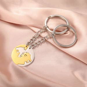 Close-up of interlocking lion couple keychains in silver and gold on pink silk