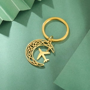 Detailed macro view of gold crescent moon keychain with celtic knot and airplane pendant
