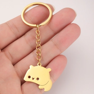 Close-up of golden bear charm keychain held in hand for size reference