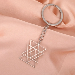 Detail of silver stainless steel keychain with interlocking geometric star pendant on pink silk