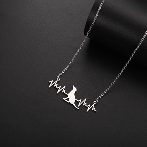 Macro detail of silver EKG heart rate and dog silhouette pendant on a delicate chain