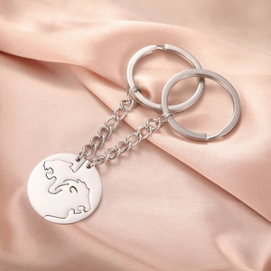 Detail of interlocking stainless steel lion couple keychains on champagne silk fabric