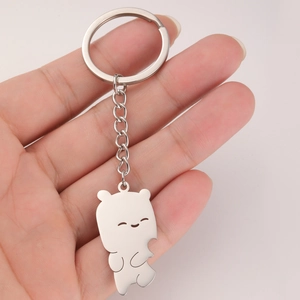Polished stainless steel bear pendant keychain held by hand for size reference