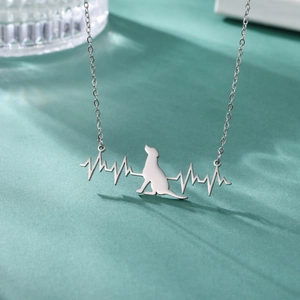 Detailed view of the EKG dog pendant and fine chain texture against a teal backdrop