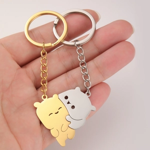 Detailed view of polished cat-shaped keychains in gold and silver held in palm