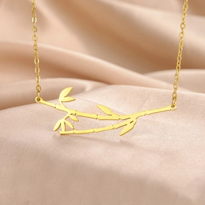 Polished gold bamboo pendant necklace made of stainless steel on champagne silk background