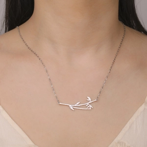 Polished silver stainless steel bamboo pendant necklace on woman's collarbone