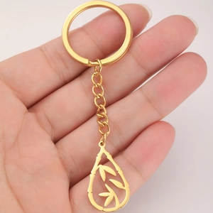 Golden stainless steel teardrop keychain with bamboo leaf cutouts held in hand