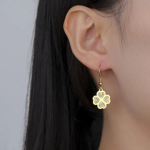 Élégantes boucles d'oreilles trèfle à quatre feuilles dorées portées par un mannequin