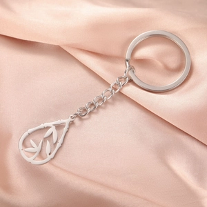 Silver stainless steel teardrop bamboo leaf keychain on pink silk background