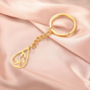 Detailed close-up of golden bamboo pendant keychain on pink silk fabric background