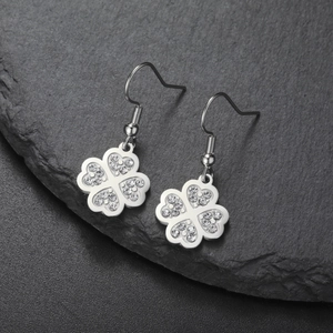 Boucles d'oreilles trèfle étincelantes en acier argenté avec zircons sur pierre foncée