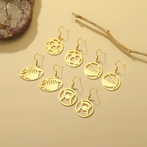 Detail of four pairs of cutout gold stainless steel sports ball earrings on a stone base