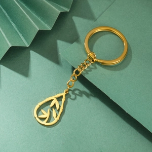 Golden stainless steel teardrop keychain with bamboo leaf design on a green background
