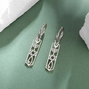 Dettaglio di orecchini in acciaio argento con simboli Menorah e Stella di David incisi