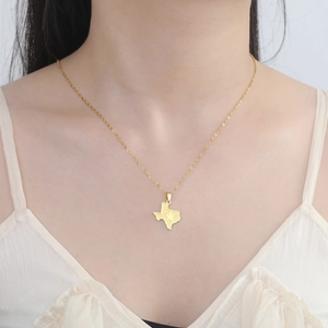 Vue rapprochée du pendentif carte du Texas doré avec étoile sur le cou d'un mannequin