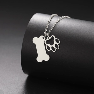 Detail van zilveren roestvrijstalen ketting met bot en holle pootafdruk hangers