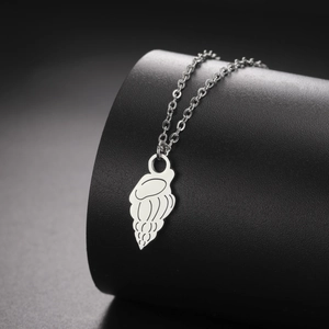 Macro detail of silver jellyfish shell pendant with grooved texture on a metallic chain