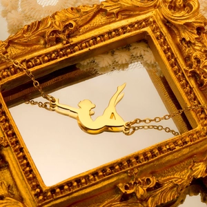 Close-up of a polished gold female silhouette pendant on a delicate chain in a frame