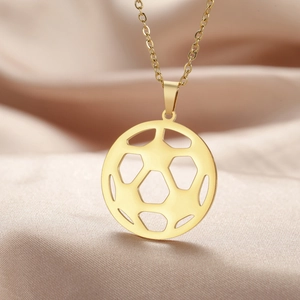 Détail d'un pendentif ballon de football doré évidé sur un fond en soie douce