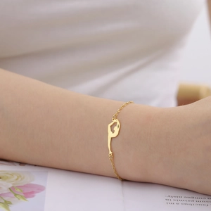 Detail shot of a delicate gold stainless steel bracelet with a gymnastics silhouette charm