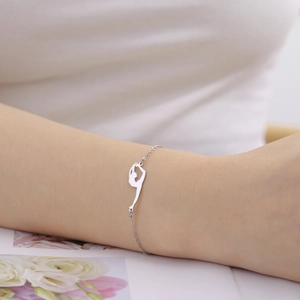 Detailed view of a silver gymnast silhouette pendant on a delicate stainless steel bracelet