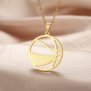 Gros plan d'un collier pendentif basket en acier doré sur soie couleur champagne