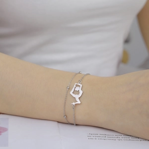 Macro detail of silver double-layered chain bracelet with rhythmic gymnastics silhouette charm